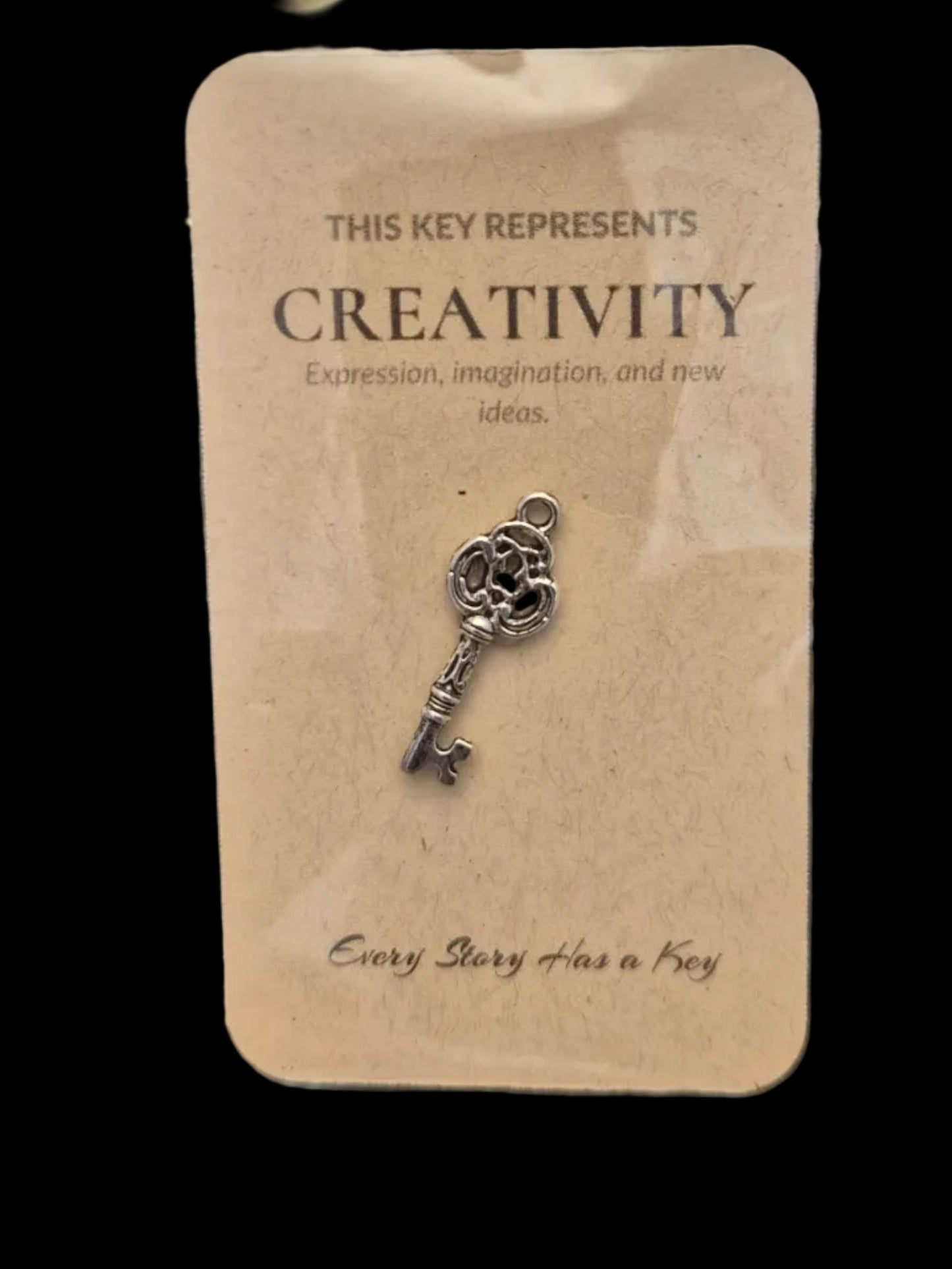 Decorative key charm on a card with text on a dark wooden surface
